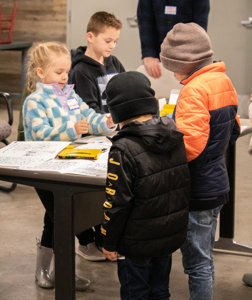 Four kids standing at a table and coloring